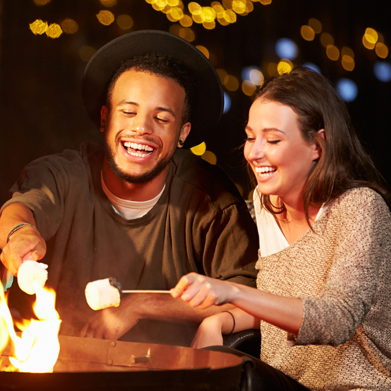 couple toasting marshmallows over firepit